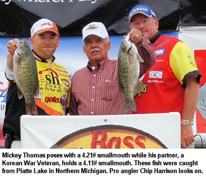 Mickey Thomas poses with a 4.21# smallmouth while his partner, a Korean War Veteran, holds a 4.11# smallmouth. These fish were caught from Platte Lake in Northern Michigan. Pro angler Chip Harrison looks on.