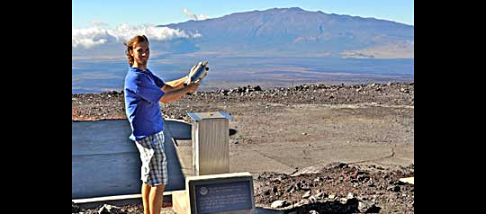 Aidan Colton at NOAA's Mauna Loa Observatory (MLO) demonstrates how early flask samples were filled at the site. Air collected year-round at MLO and eight other remote sites around the world has been analyzed for the industrial solvent methyl chloroform. Variability in the decay of this chemical has helped scientists understand the oxidizing or cleansing power of the global atmosphere and its sensitivity to natural and human-induced perturbations. Photo Credit: NOAA
